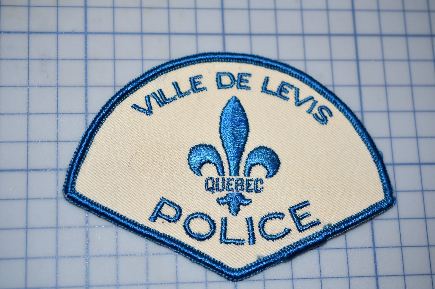 a patch with a blue and white fleur de levi's police logo