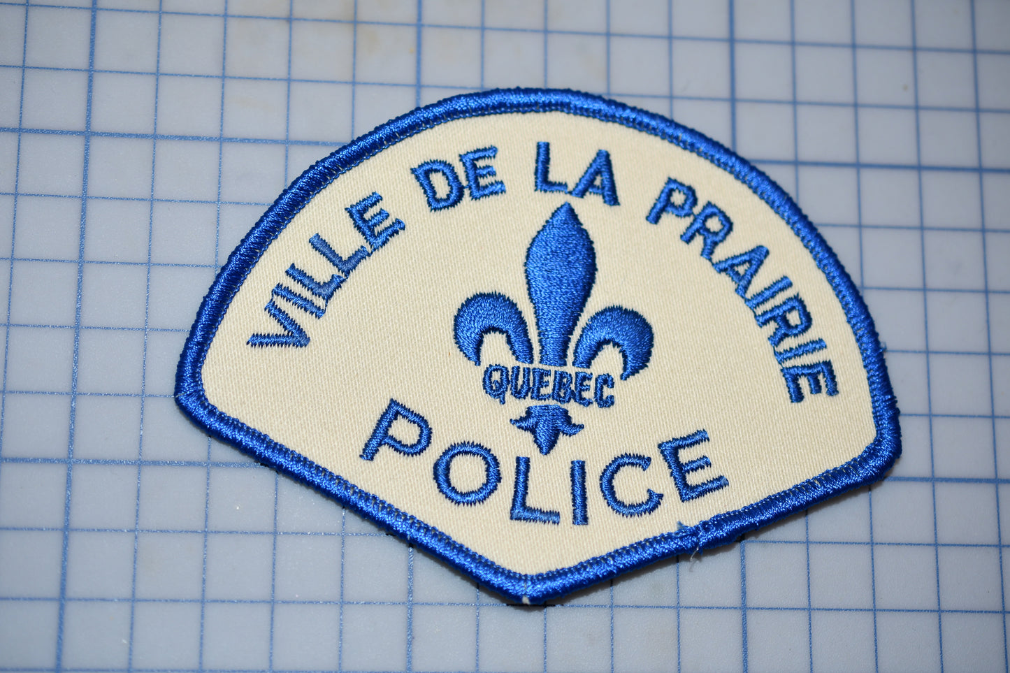 a police patch with a fleur de la prairie police badge